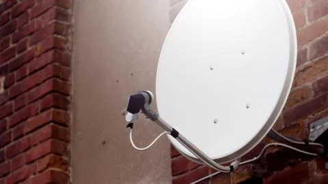 White satellite dish on the brick background Stock Photos