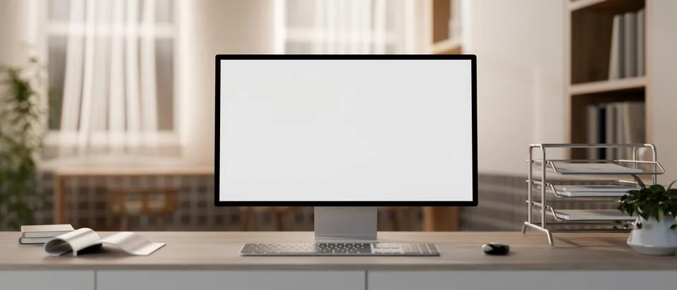 A white-screen computer mockup and office supplies on a table in a cozy con.. Illustrazione stock