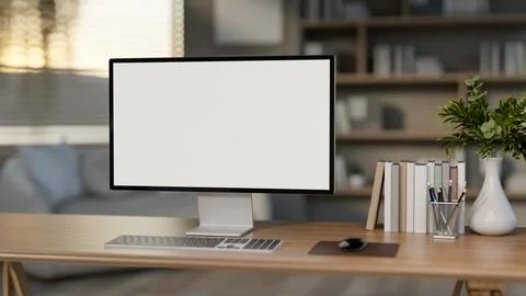 The white screen computer on the wooden table with books and decors in the .. Stock Illustration