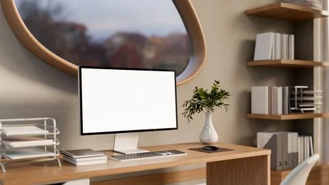 White screen computer on wooden table under oval window with forest scenery.. Illustrazione stock