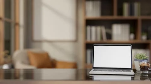 White screen laptop aside coffee and potted plant on glass top wooden table.. Illustrazione stock