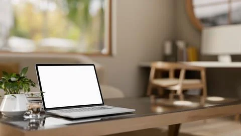 White screen laptop with coffee cup and books on glass top wooden table in .. Illustrazione stock