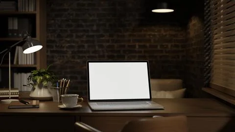 White screen laptop with coffee in lamp light on table across bookshelf and.. Illustrazione stock
