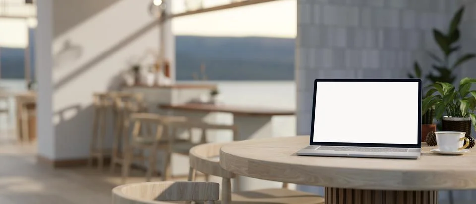 A white-screen laptop computer mockup on a table in a modern, Scandinavian .. Illustrazione stock