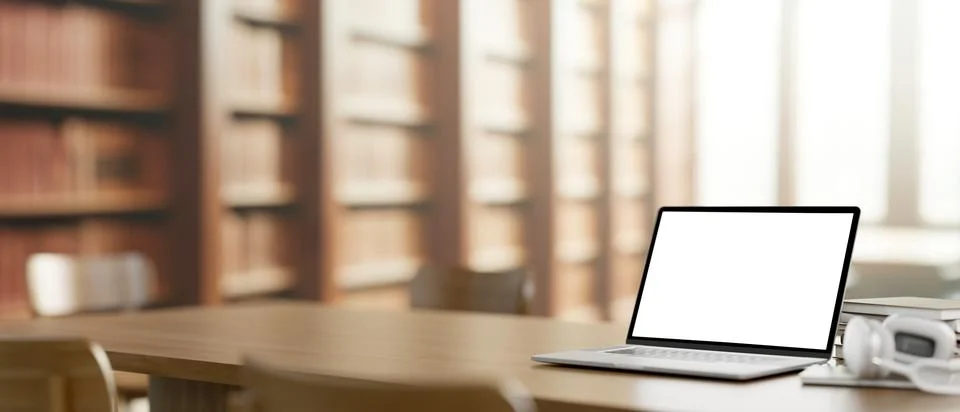 A white-screen laptop computer mockup on a wooden table in a library. Stock Illustration