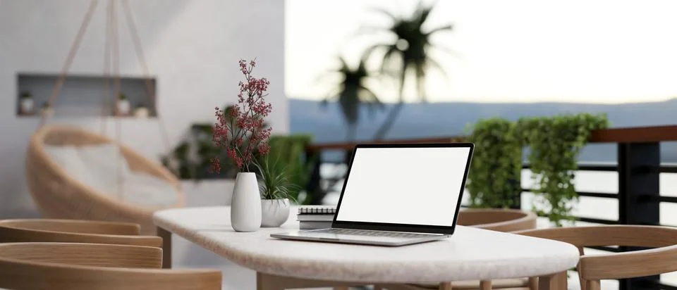 A white-screen laptop computer on a table on a beautiful home balcony. Home.. Illustrazione stock
