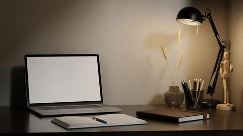 White screen laptop with pen on open notebook under warm lamp light on tabl.. 스톡 일러스트