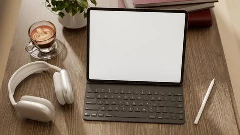 White screen tablet with keyboard and pen aside coffee cup and headphones o.. Illustrazione stock