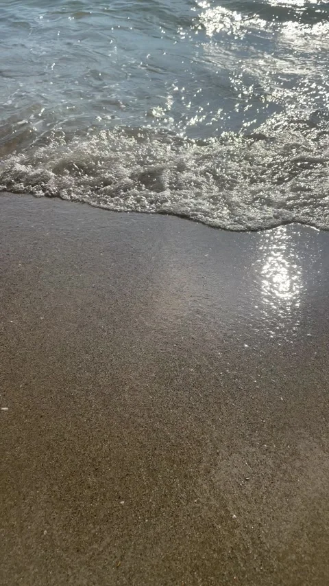 White Sea Foam Patterns Spreading Across Sunlit Shallow Water and Wet Sand Video stock 204734761