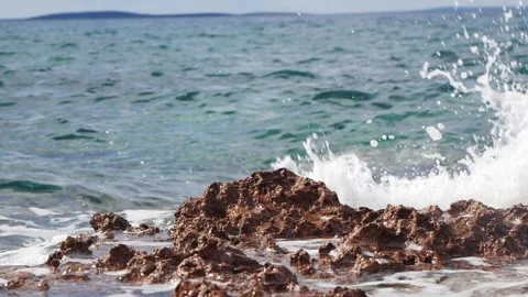 White sea foam splashes over jagged rocks along the coast. Stock Footage 337406650