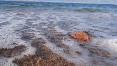 White sea foam washes over wet sand and small rocks. Stock Footage 337406061