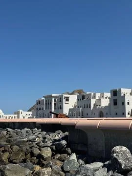 White seafront palace with old cannon and rocky shore in Muscat, Oman Stock Photos