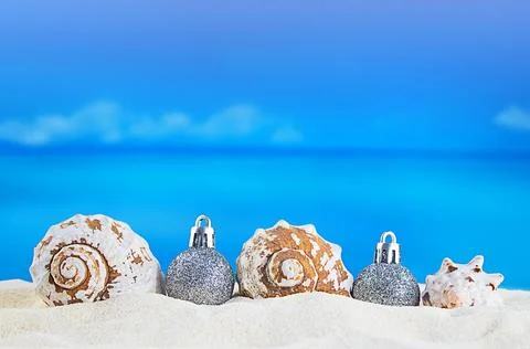 White seashells with Christmas tree silver shiny balls on the sand Stock Photos