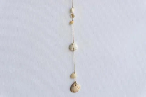 White seashells hanging in the middle of a white background. Summer home hand Stock Photos