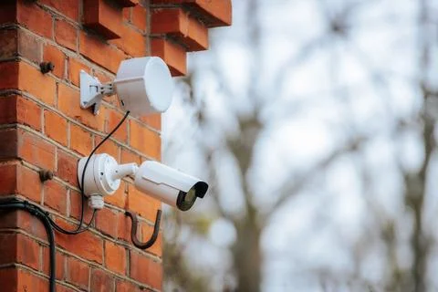 A white security camera and a motion sensor light are mounted 写真素材