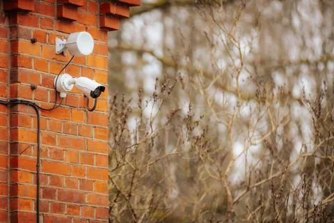 A white security camera and a motion sensor light are mounted 写真素材