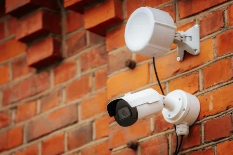 A white security camera and a motion sensor light are mounted 写真素材