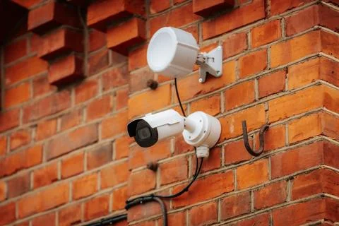 A white security camera and a motion sensor light are mounted 写真素材