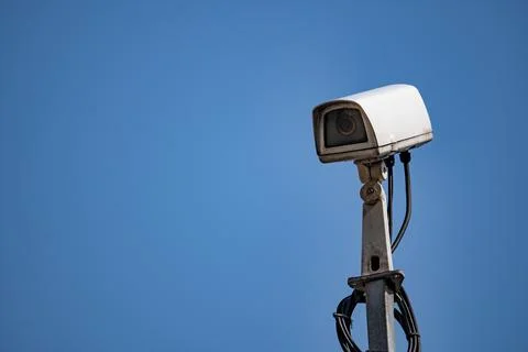 White Security Camera Mounted on Pole Against Blue Sky Stock Photos