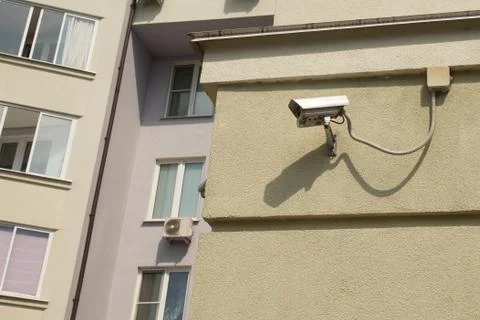 White security surveillance camera on the wall of a apartment house. Concept Stock Photos