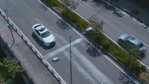 A white Self-driving car is driving across the road. 4K. Drone Stock Footage