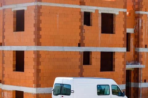 White service van parked outside a multi-story residential building under c.. Stockfoto's