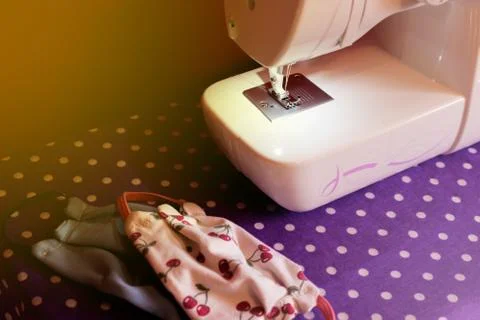 White sewing machine resting on a table next to homemade chinstraps in colorf Stock Photos