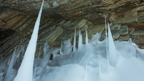 White sharp frozen icicles, stalagmites formed on floor at ice cave in huge rock Stock Footage 166567657