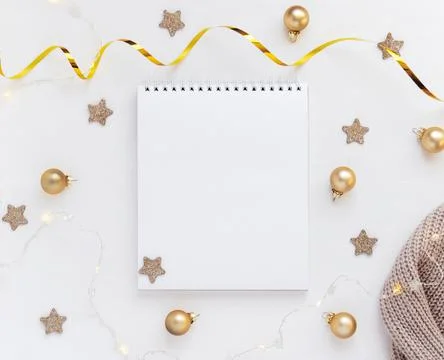White sheet of notebook on white table with stars, Christmas balls and festive Stock Photos