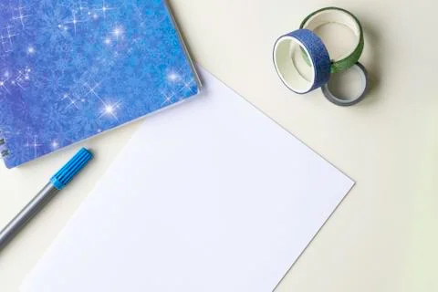 A white sheet of paper, a blue note with snowflakes, a felt-tip pen and a shi Stock Photos