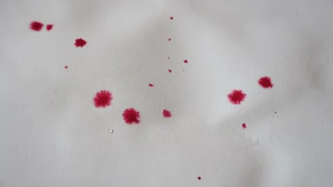 A white sheet of paper. Drops of red-colored water fall on the leaf and spread 動画素材 234123306