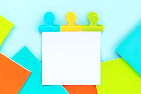 A white sheet for writing attached by three multi-colored stationery clips Stock Photos