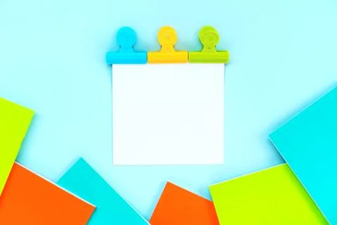 A white sheet for writing attached by three multi-colored stationery clips Foto stock
