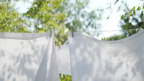 White sheets held up with clothes pegs on a washing line outside Stock Footage 239710421