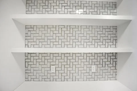 White shelf with a white tile pattern on the wall Stockfoto's