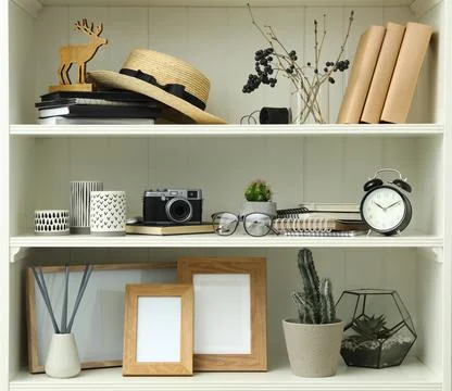 White shelving unit with photo frames and different decorative elements Stock Photos