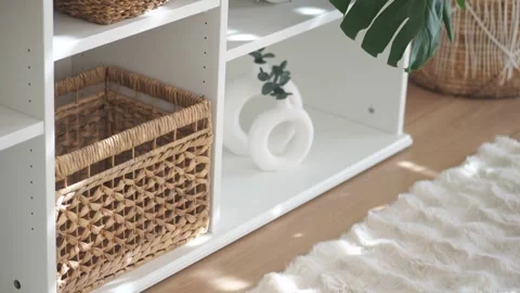 White shelving unit with wicker baskets and minimalist decor in sunlit mode.. Stock Footage 331725633
