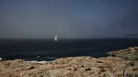 A white ship with a sail moves across the blue sea in a fog view from the ocean Stock Footage 229504707