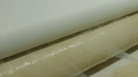 White, silky fabric passing through a roller machine to be cleaned in a textile  Stock Footage 291871020