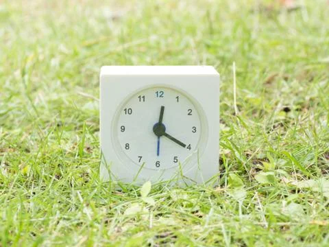 White simple clock on lawn yard, 12:20 twelve twenty Stock Photos