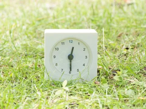 White simple clock on lawn yard, 12:30 twelve thirty half Stock Photos