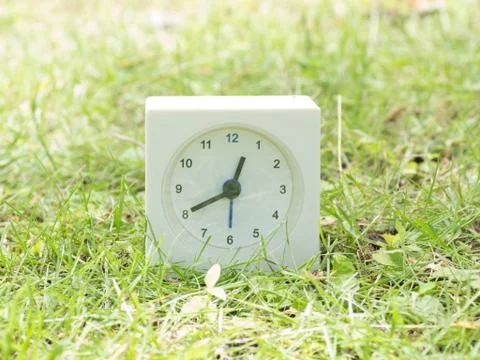 White simple clock on lawn yard, 12:40 twelve forty Stock Photos