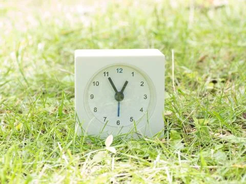 White simple clock on lawn yard, 12:55 twelve fifty five Stock Photos