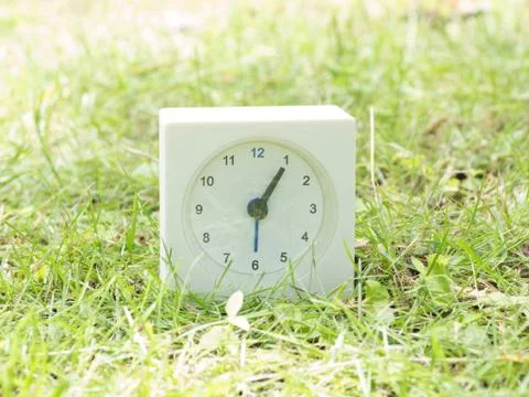 White simple clock on lawn yard, 1:05 one five Stock Photos