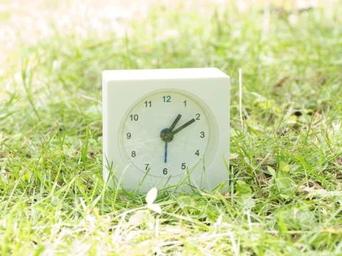 White simple clock on lawn yard, 1:10 one ten Stock Photos