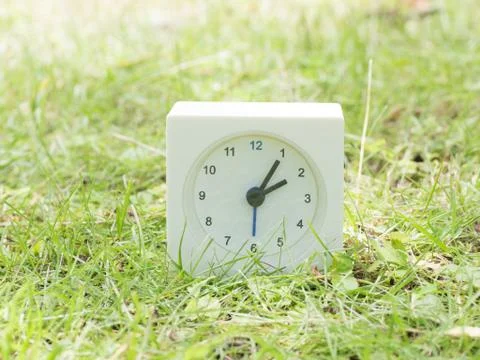 White simple clock on lawn yard, 2:05 two five Stock Photos