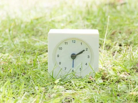 White simple clock on lawn yard, 2:10 two ten Stock Photos