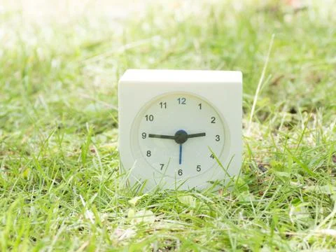 White simple clock on lawn yard, 2:45 two forty five Stock Photos