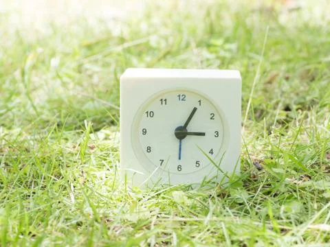 White simple clock on lawn yard, 3:05 three five Stock Photos