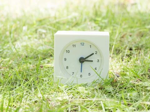 White simple clock on lawn yard, 3:10 three ten Stock Photos